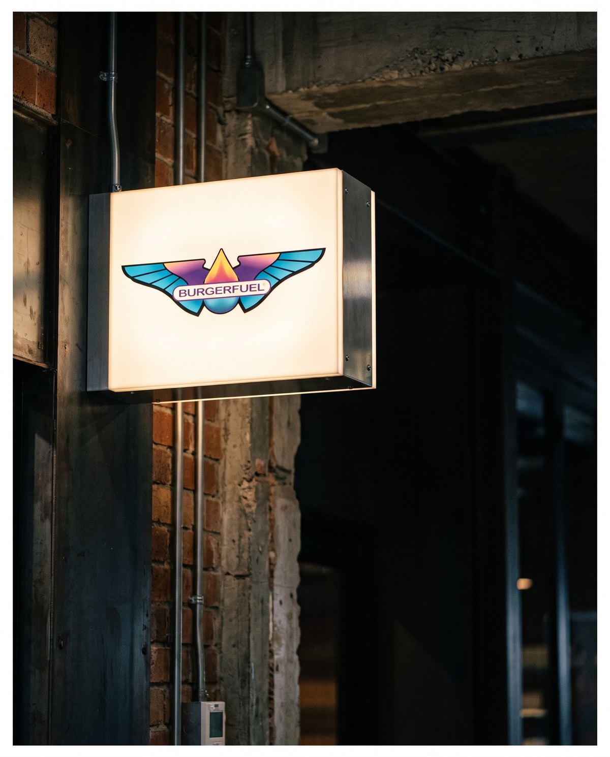 Illuminated BurgerFuel light box on an industrial wall