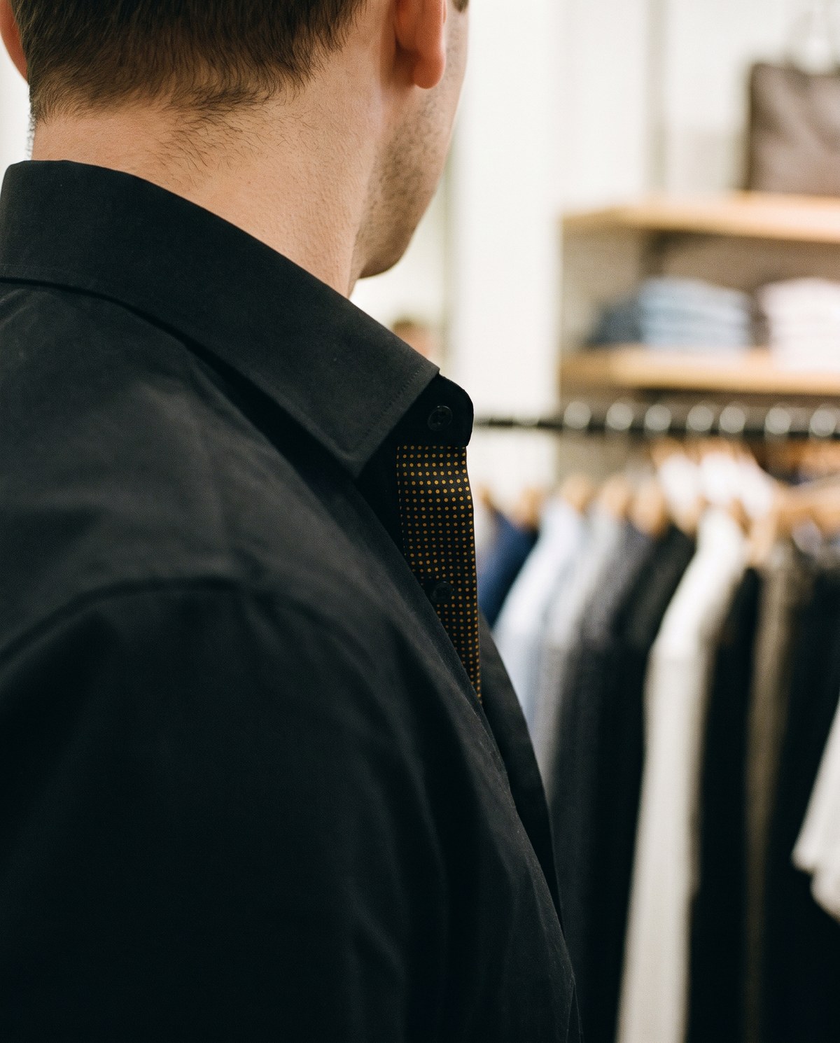 A store associate turned away, the inside of the shirt placket printed with a dot field