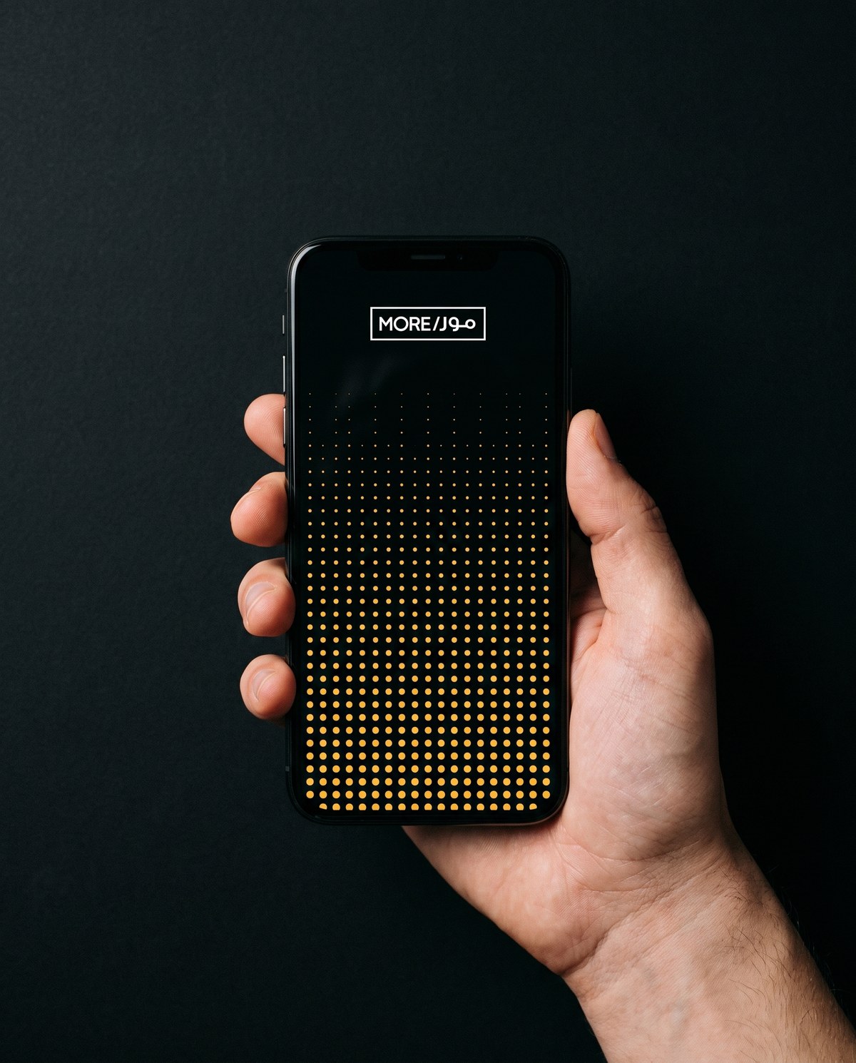 A phone showing a MORE social advertisement built from a rising field of dots