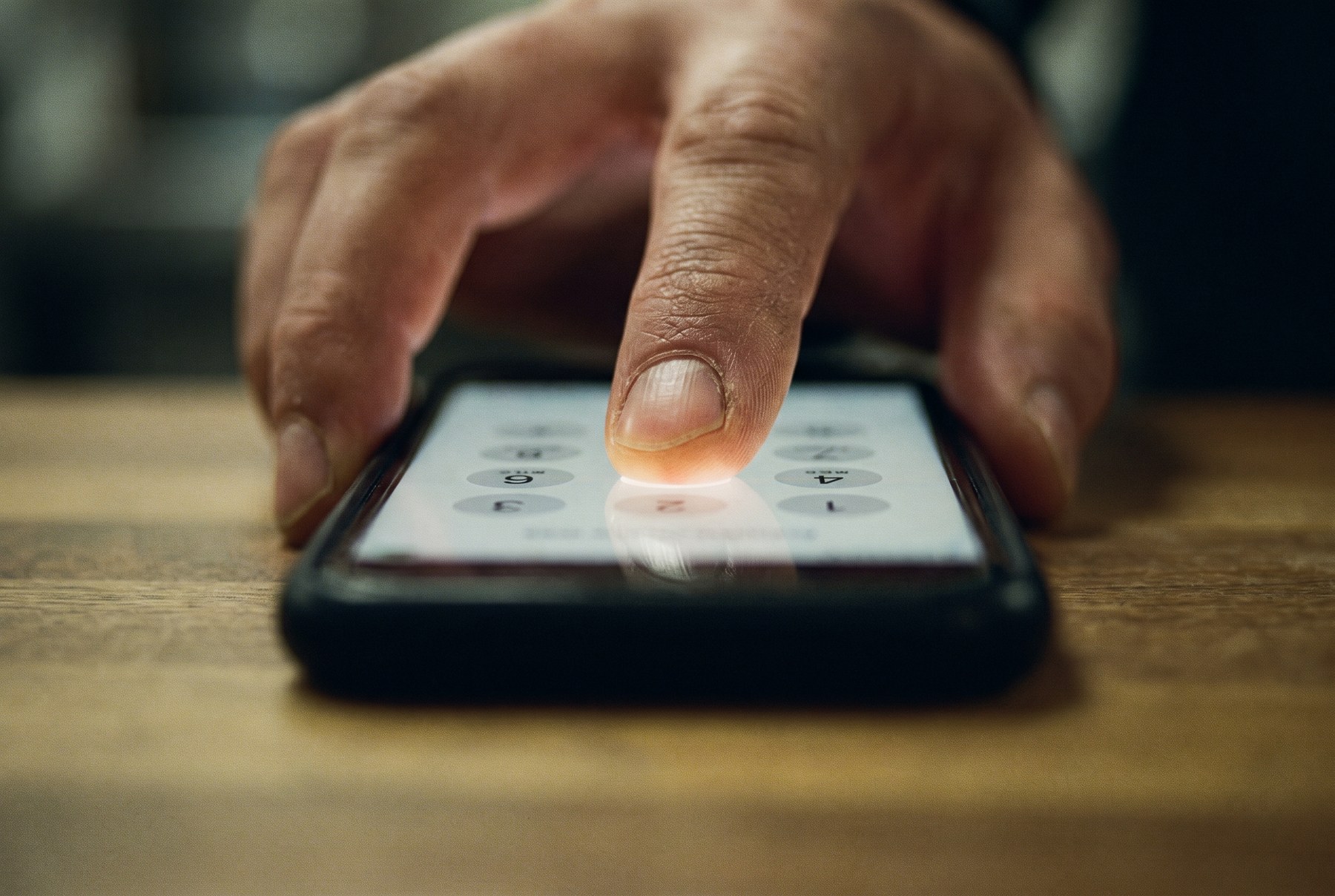 A thumb pressing a key on a phone number pad at a shop counter
